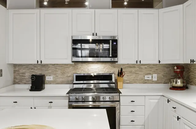 a kitchen with white cabinets and appliances