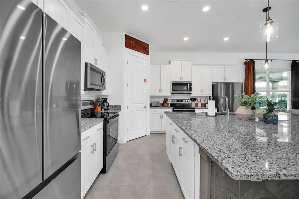 1213 Radiant Street Reunion, FL 34747 - Photo 26 of 84 a kitchen with stainless steel appliances granite countertop a refrigerator a stove top oven a sink and dishwasher