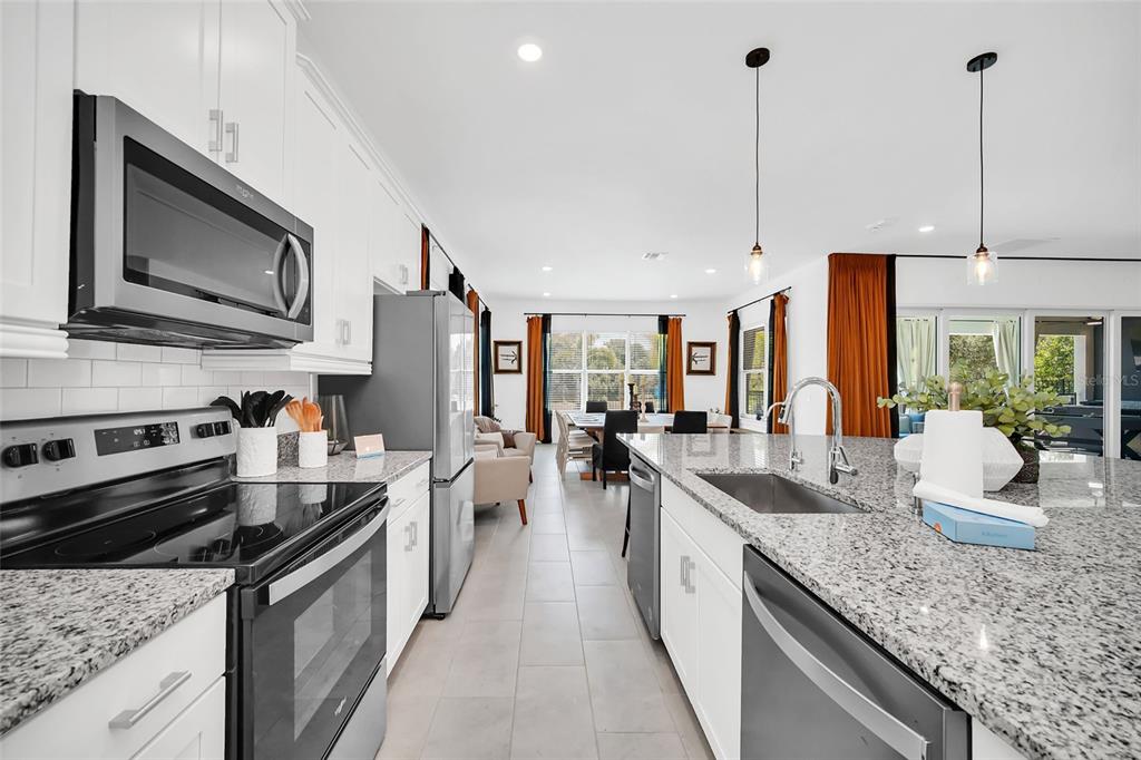 1213 Radiant Street Reunion, FL 34747 - Photo 29 of 84 a kitchen with stainless steel appliances granite countertop a sink a stove and a wooden floors
