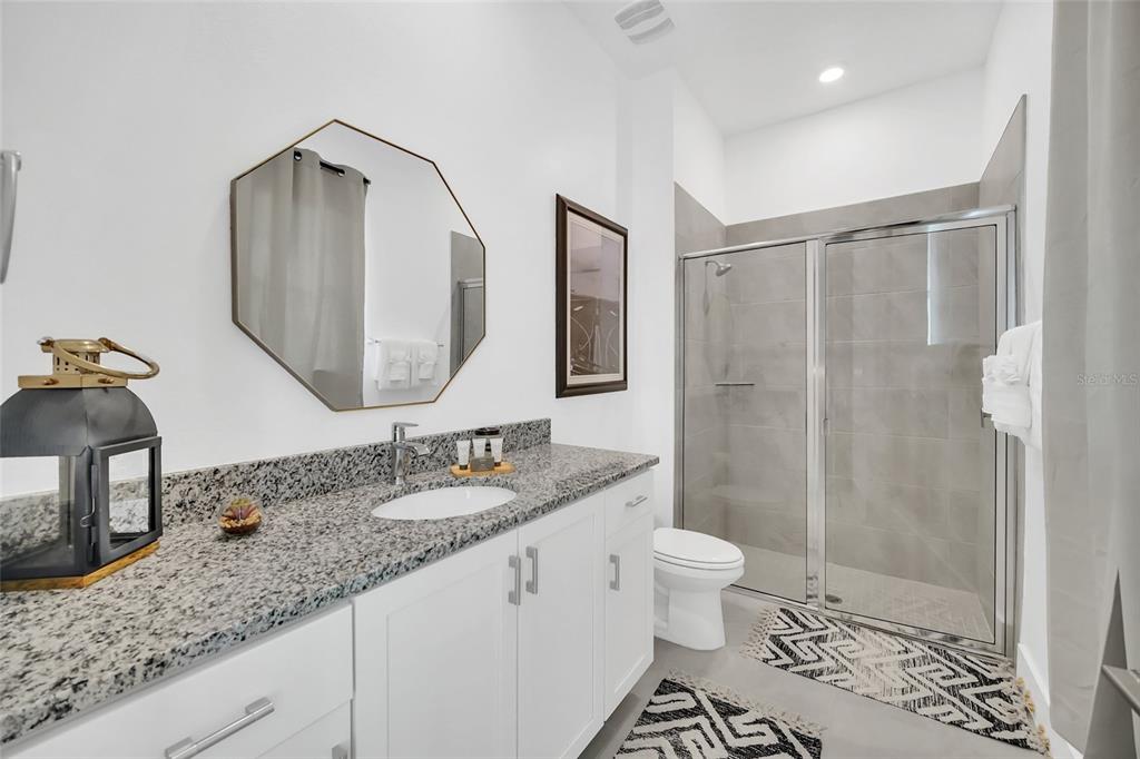 1213 Radiant Street Reunion, FL 34747 - Photo 50 of 84 a bathroom with a granite countertop sink a toilet and a mirror