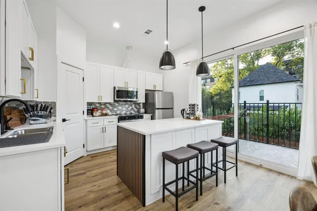 a kitchen that has a lot of white cabinets and wooden floor
