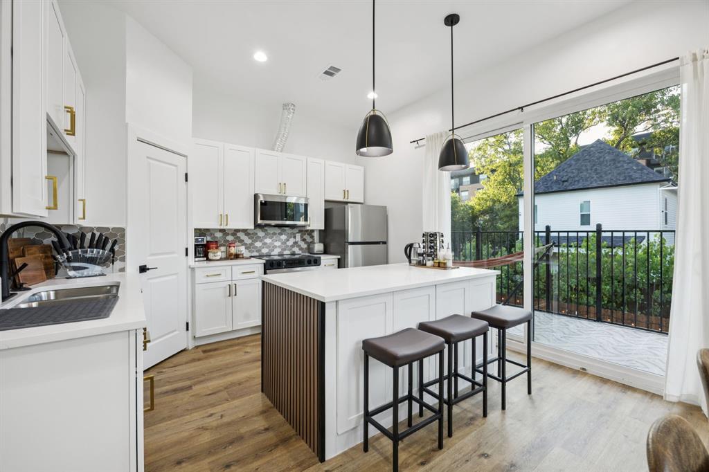 907 Bayonne Street Dallas, TX 75212 - Photo 13 of 38 a kitchen with kitchen island granite countertop a stove a sink a refrigerator with a dining table and chairs