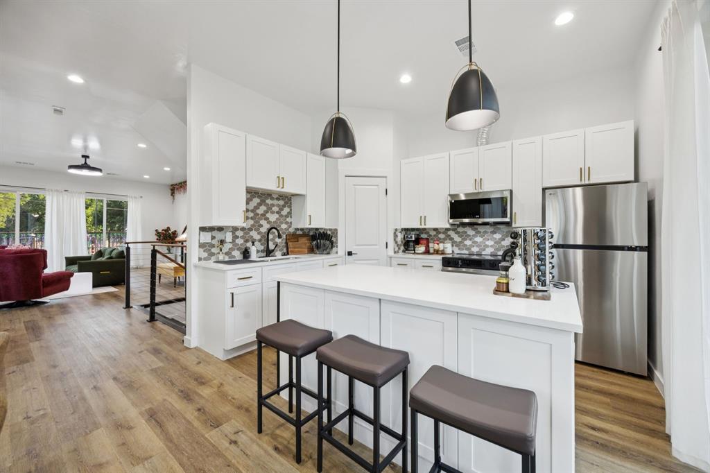 907 Bayonne Street Dallas, TX 75212 - Photo 15 of 38 a kitchen with stainless steel appliances kitchen island a refrigerator a stove a oven and white cabinets with wooden floor