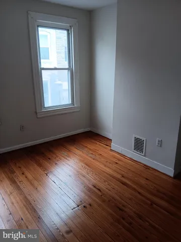 a view of an empty room with wooden floor and closet