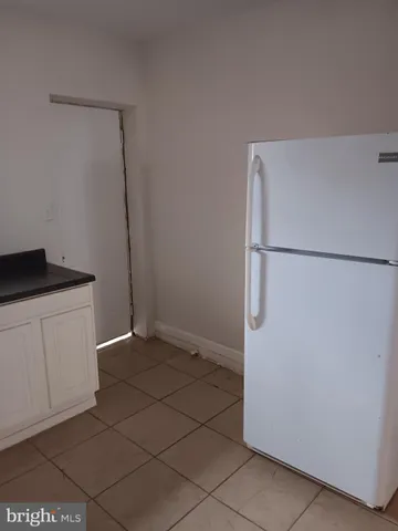 a view of a refrigerator in kitchen and white cabinets