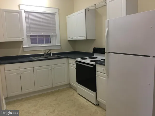 a kitchen with stainless steel appliances granite countertop a refrigerator sink and white cabinets