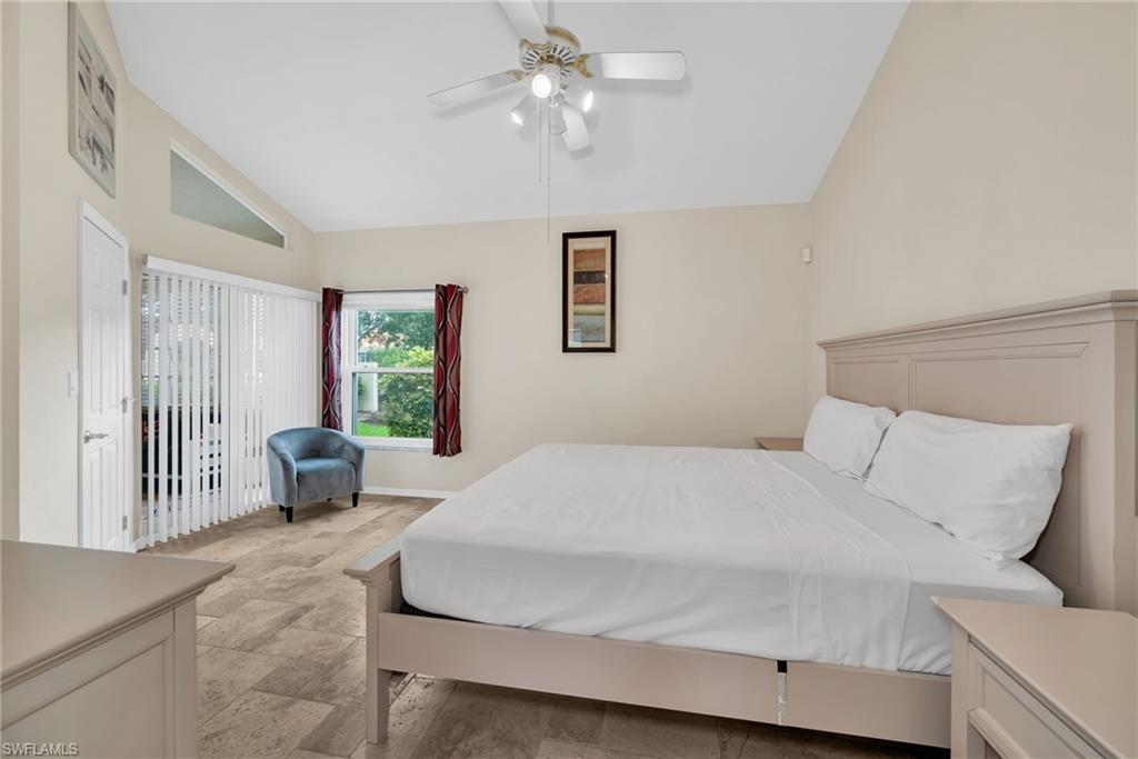 181 Napa Ridge Road East, Unit 35 Naples, FL 34119 - Photo 10 of 21 Vaulted ceiling bedroom with a ceiling fan, light-toned tile flooring, and a sliding glass door with vertical blinds
