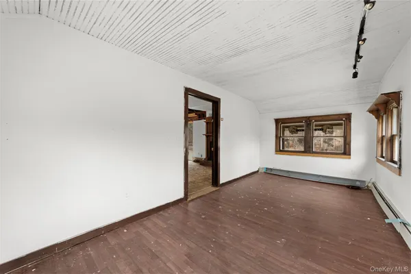 a view of an empty room with a window and wooden floor