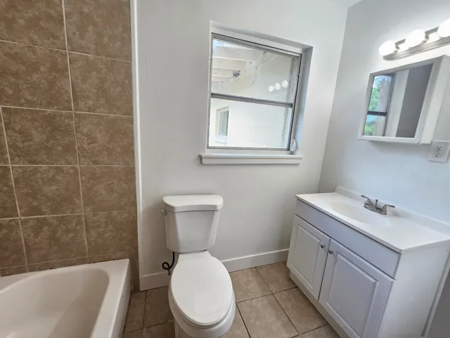 a bathroom with a toilet a sink a mirror a bathtub and shower