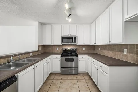 a white kitchen with granite countertop white cabinets a sink and dishwasher
