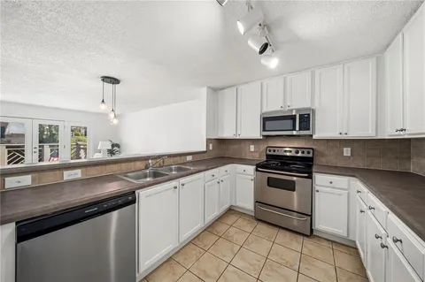 a kitchen with granite countertop white cabinets stainless steel appliances and a sink