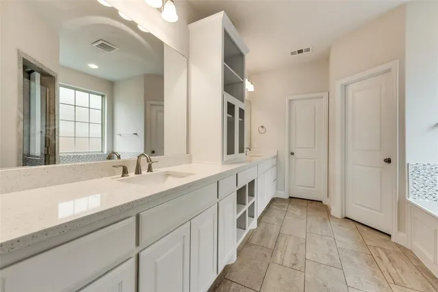 a spacious bathroom with a double vanity sink a mirror and a bathtub