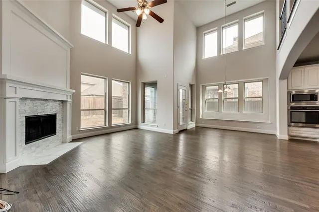 an empty room with wooden floor fireplace and windows