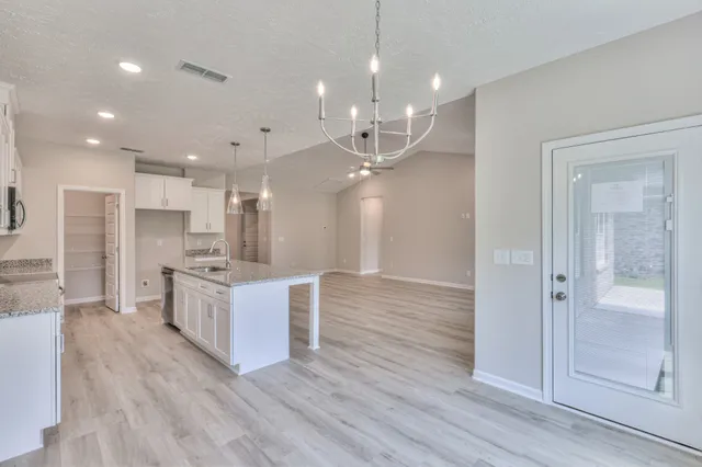 a large kitchen with granite countertop a large counter top a sink stainless steel appliances and cabinets