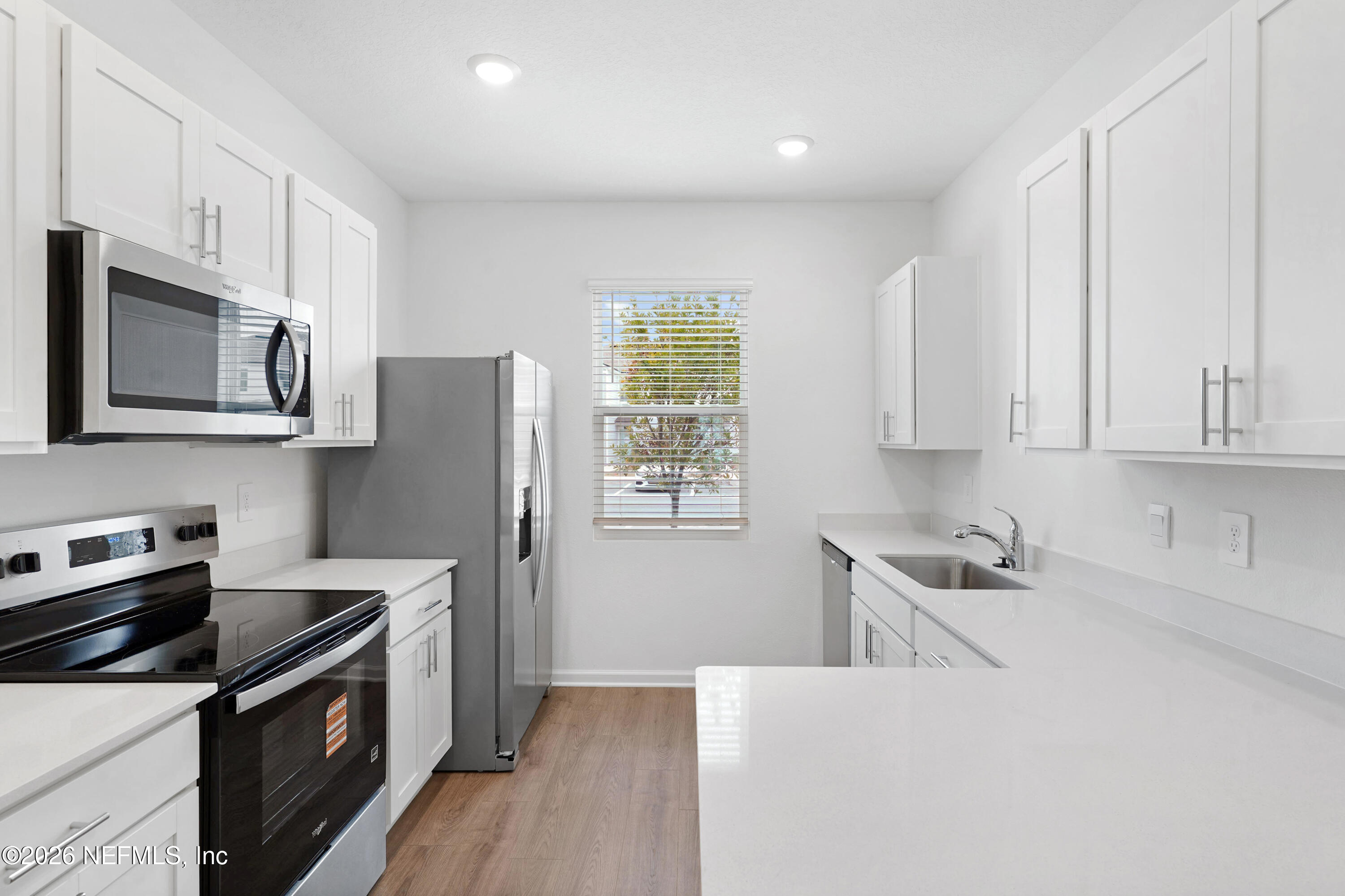 131 Palmetto Rdg Road St. Augustine, FL 32095 - Photo 4 of 26 a kitchen with stainless steel appliances granite countertop white cabinets a sink a stove a refrigerator and microwave with wooden floor