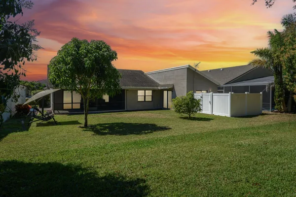 a view of a house with a big yard and large trees