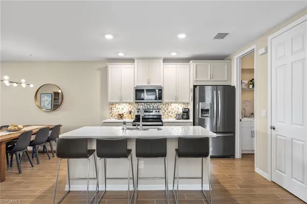 a kitchen with stainless steel appliances kitchen island granite countertop a table and chairs in it