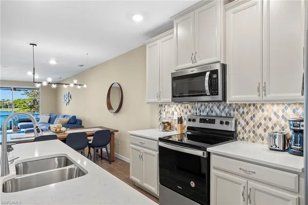 a kitchen with stainless steel appliances granite countertop a sink a stove a dining table and chairs