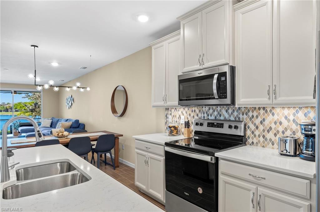 14644 Edgewater Circle Naples, FL 34114 - Photo 7 of 37 a kitchen with stainless steel appliances granite countertop a sink a stove a dining table and chairs