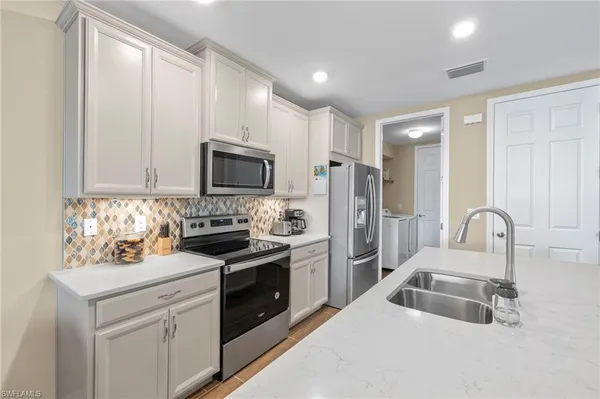 a kitchen with white cabinets and stainless steel appliances