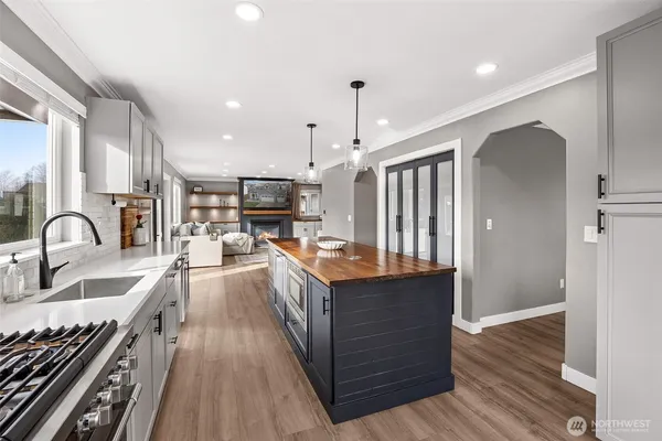 a kitchen with stainless steel appliances granite countertop a stove top oven a sink dishwasher a refrigerator and a dining table with wooden floor