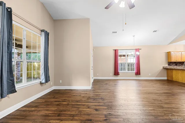 a view of an empty room with window and wooden floor