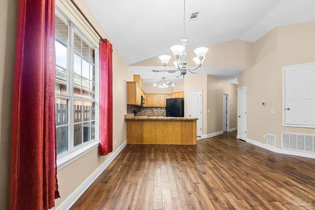 a view of a kitchen with kitchen island wooden floor and stainless steel appliances