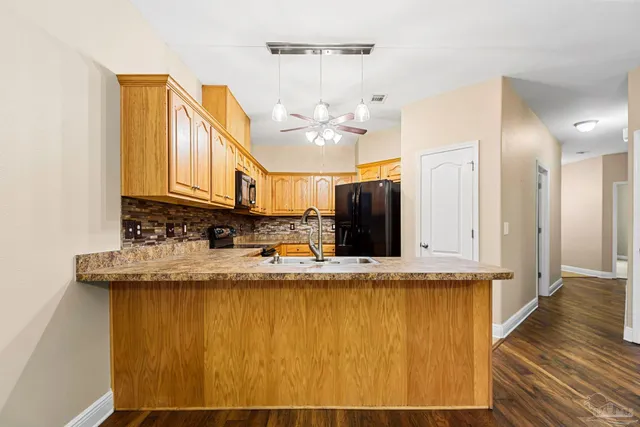 a view of a kitchen with granite countertop a sink and dishwasher a stove with wooden floor