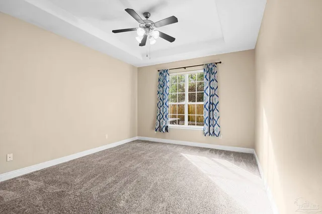 an empty room with windows and ceiling fan