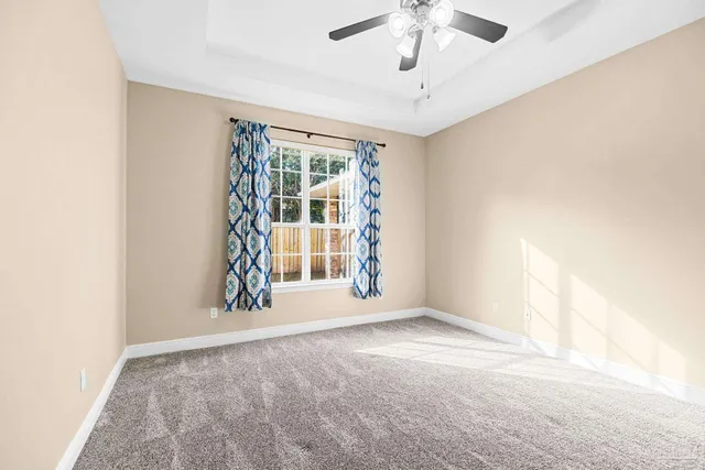 an empty room with windows and ceiling fan