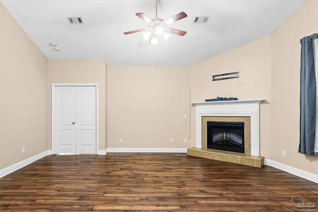 a view of an empty room with chandelier fan and wooden floor