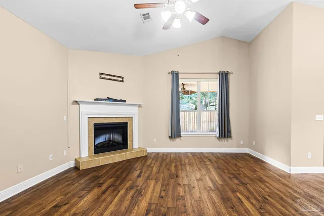 an empty room with wooden floor fireplace and windows