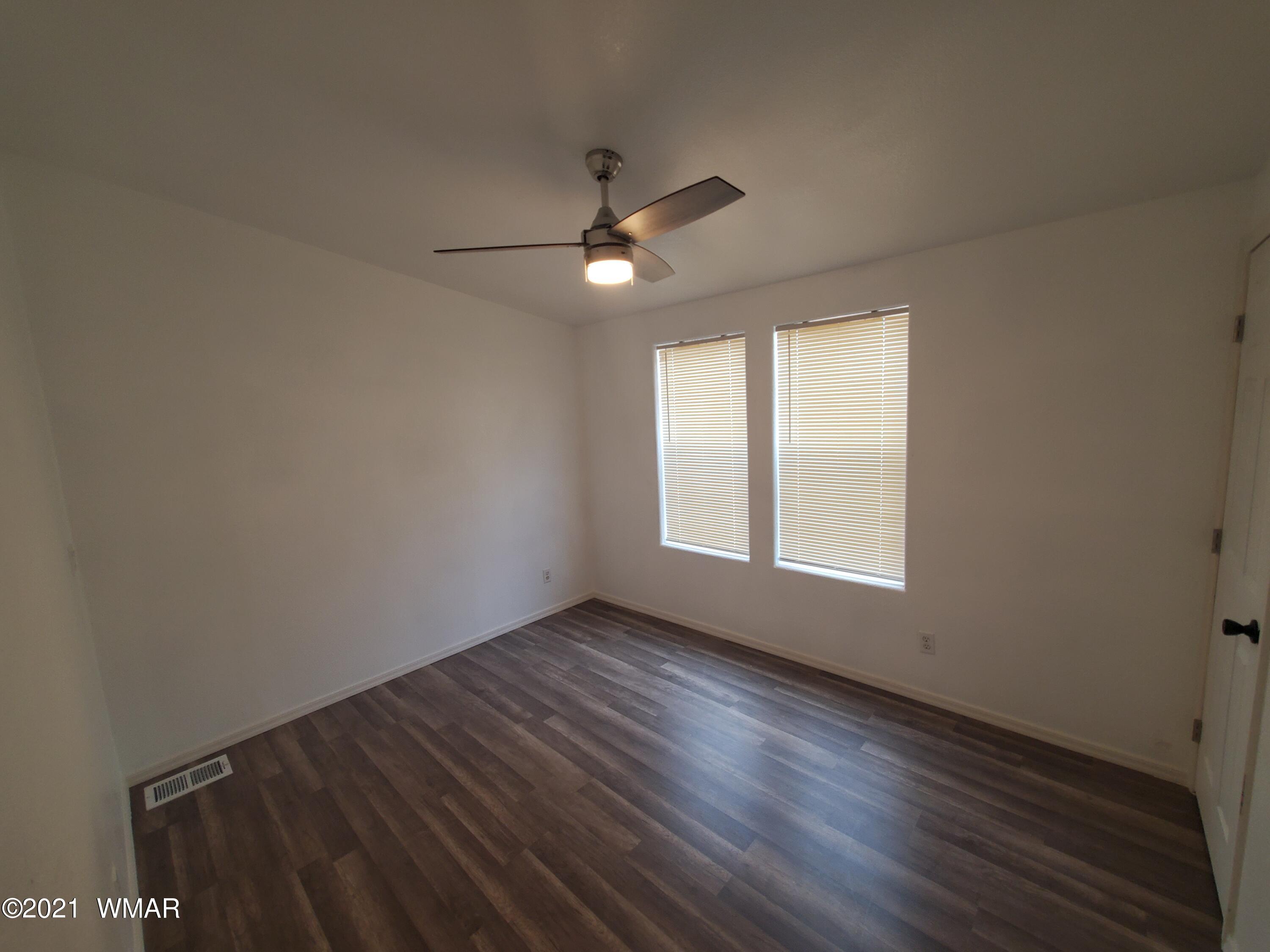 181 River Spings Ranch St. Johns, AZ 85936 - Photo 12 of 60 an empty room with wooden floor ceiling fan and windows