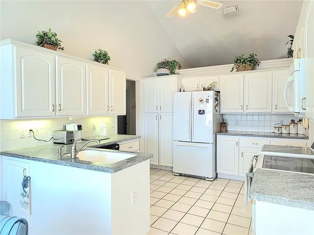 a kitchen with stainless steel appliances granite countertop a refrigerator sink and white cabinets