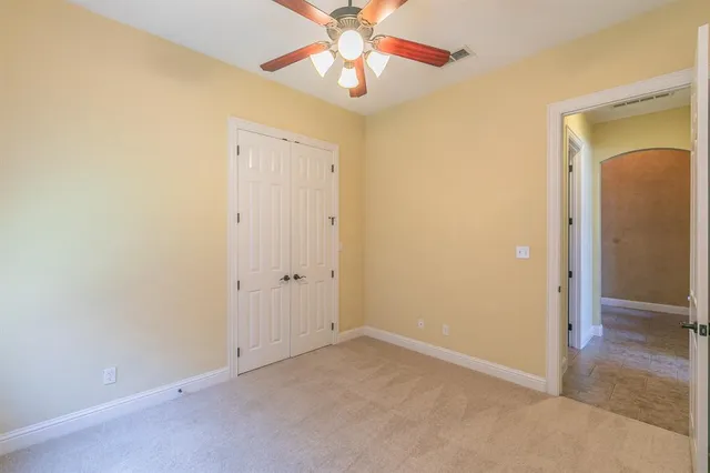 an empty room with a chandelier fan and closet area