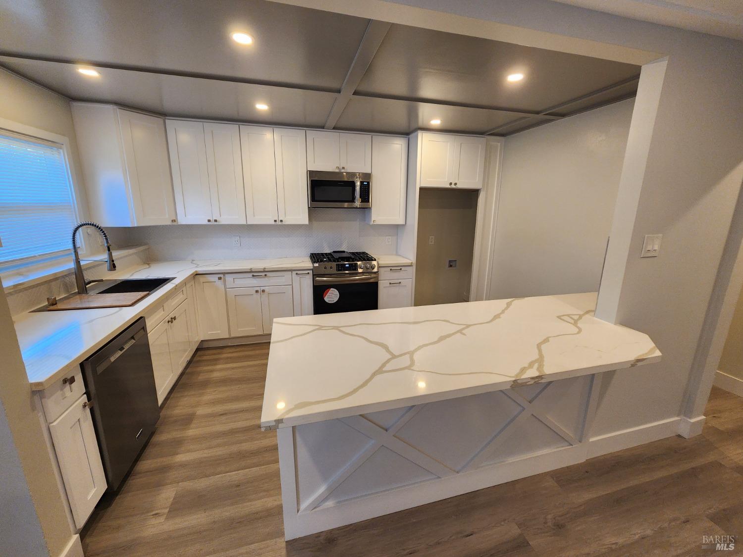 a large white kitchen with wooden floor