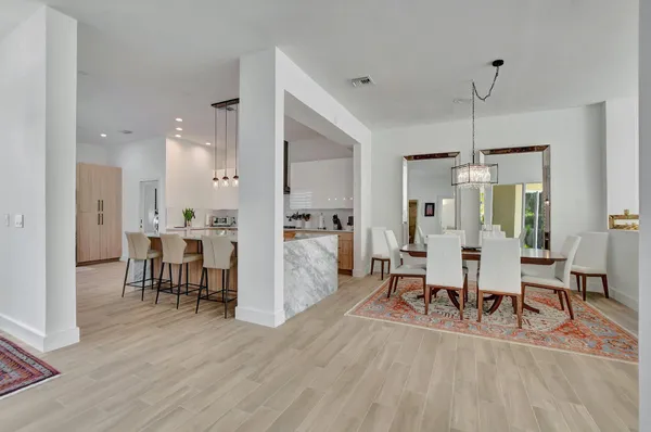 a view of a a dining room and livingroom with furniture wooden floor a chandelier