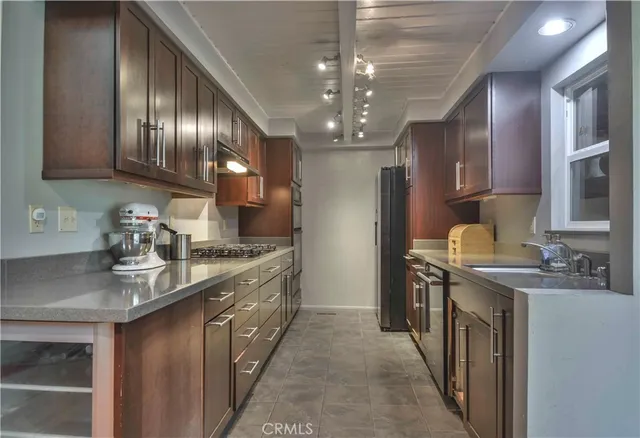 a kitchen with stainless steel appliances granite countertop a sink a stove oven a refrigerator with wooden cabinets and floor