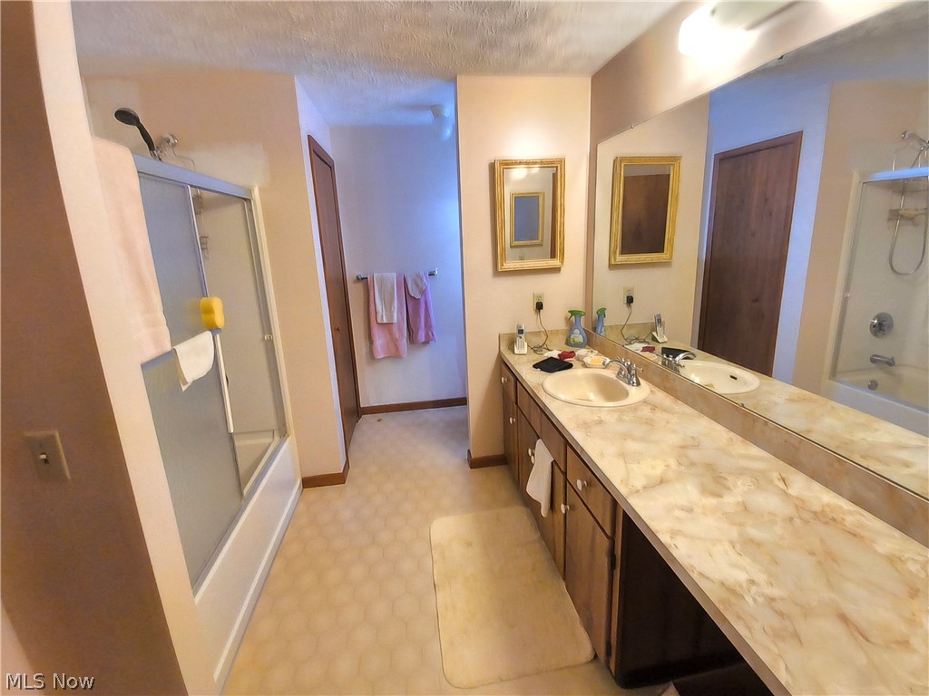 2672 Crackel Road Aurora, OH 44202 - Photo 14 of 38 Bathroom featuring shower / bath combination with glass door, light flooring, vanity, and a textured ceiling