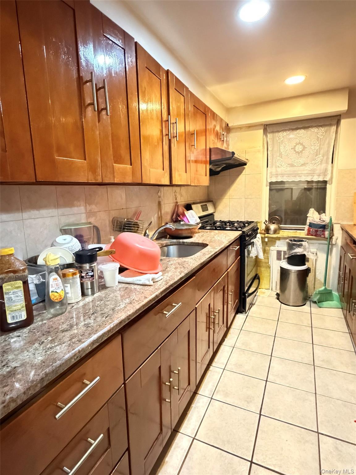 134-39 Blossom Avenue, Unit 2G Queens, NY 11355 - Photo 2 of 5 Kitchen featuring brown cabinets, light stone countertops, stainless steel gas stove, light tile patterned flooring, and recessed lighting