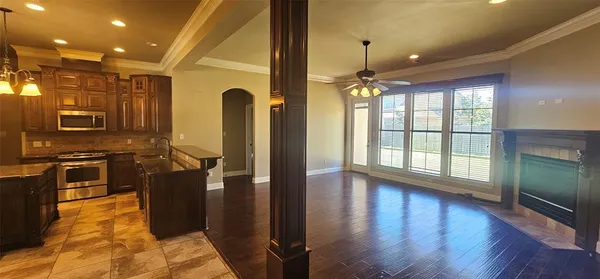 a view of an empty room with wooden floor and a fireplace