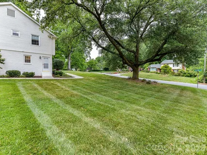 a view of a house with a big yard and large trees