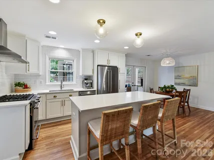 a kitchen with stainless steel appliances granite countertop a stove a sink a refrigerator with a dining table and chairs