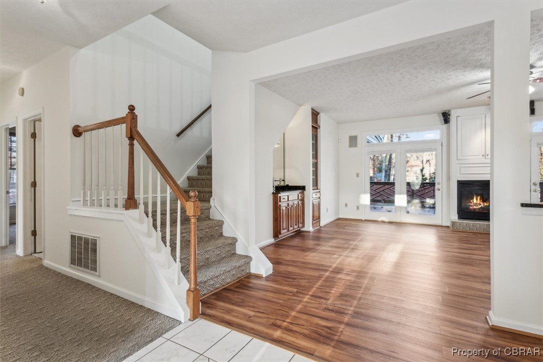 Entrance foyer with a textured ceiling, light hardwood / wood-style floors, and a fireplace