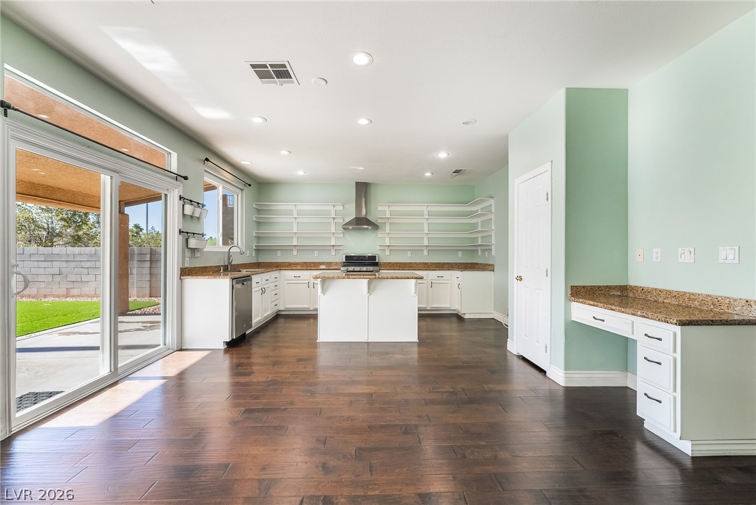 261 Timber Hollow Street Henderson, NV 89012 - Photo 14 of 51 A well-lit kitchen with rich hardwood floors and ample granite counter space, connecting to an outdoor patio.