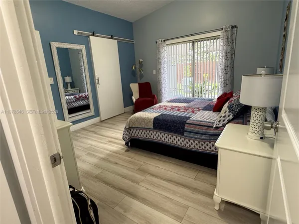 a bedroom with a bed wooden floor and window