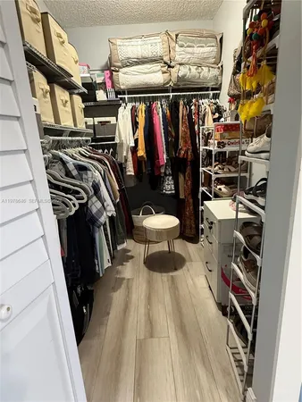 a view of walk in closet with clothes and shoes