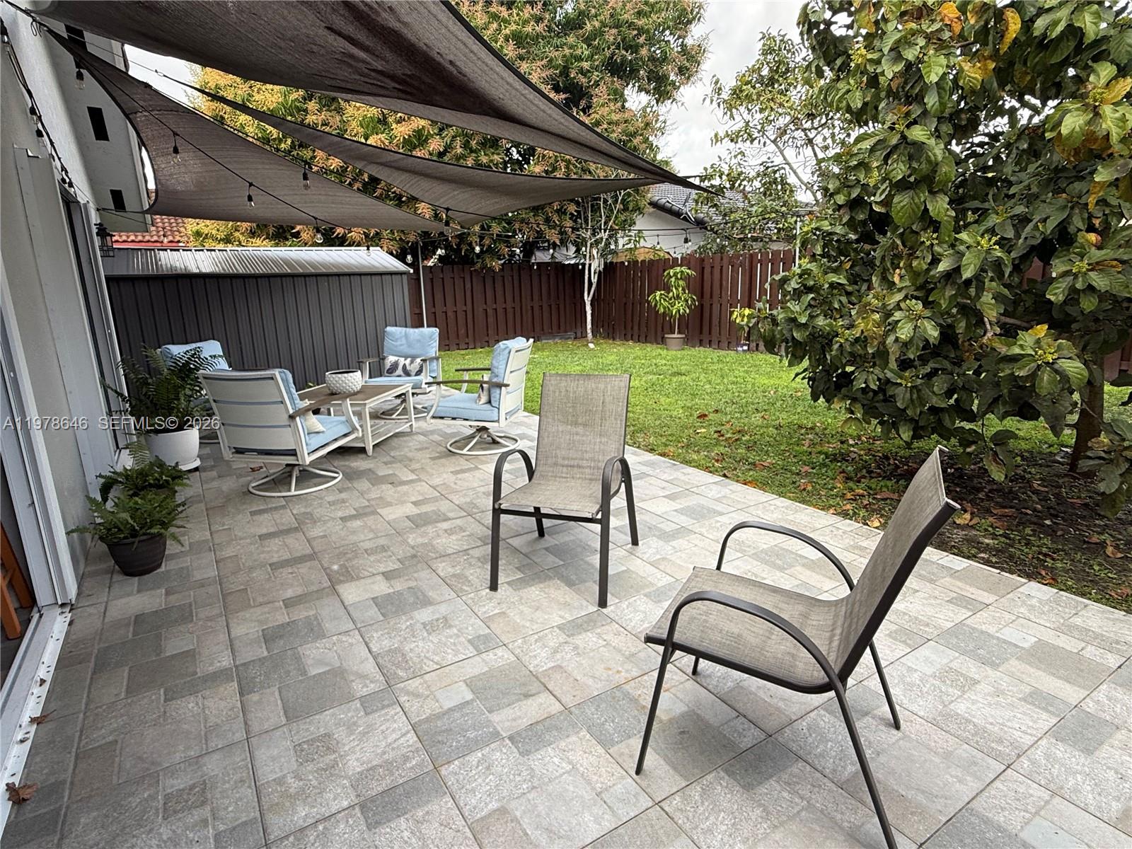 13833 Southwest 157th Street Miami, FL 33177 - Photo 22 of 25 a view of a patio with a table and chairs under an umbrella with a small yard