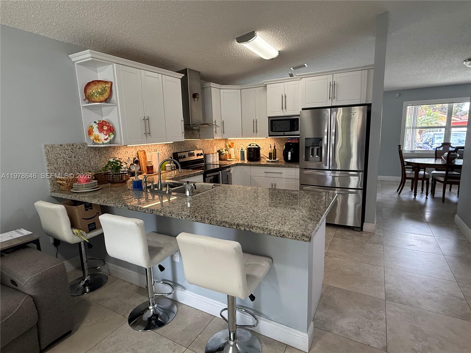 13833 Southwest 157th Street Miami, FL 33177 - Photo 6 of 25 a kitchen with granite countertop a table chairs microwave and refrigerator