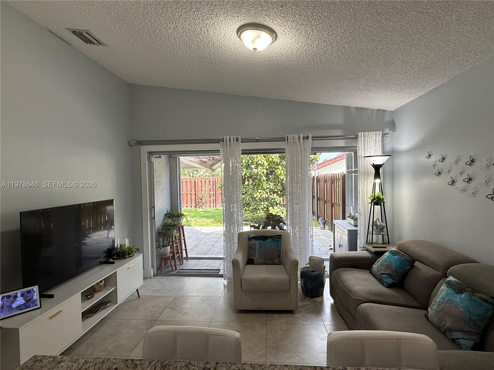 13833 Southwest 157th Street Miami, FL 33177 - Photo 9 of 25 a living room with furniture and a flat screen tv